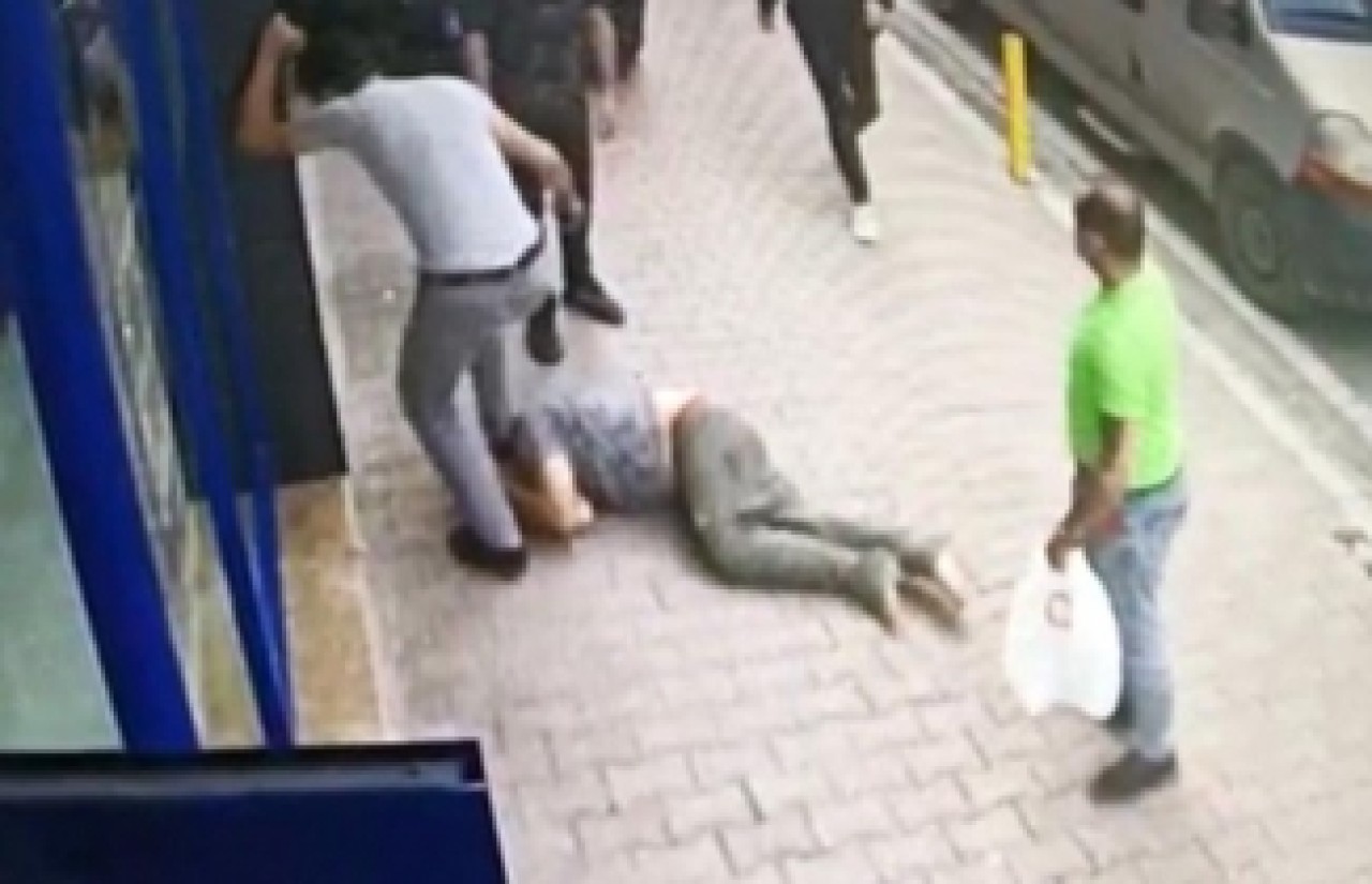 Çocuklardan para isteyen adamı,  yerde tekmeleyerek dövdüler
